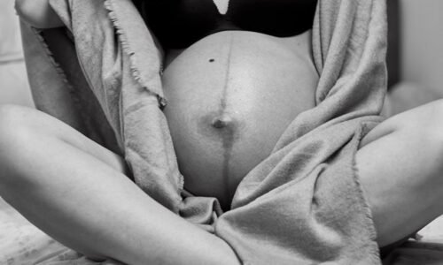 Artistic black and white maternity photo showing a pregnant woman's belly.