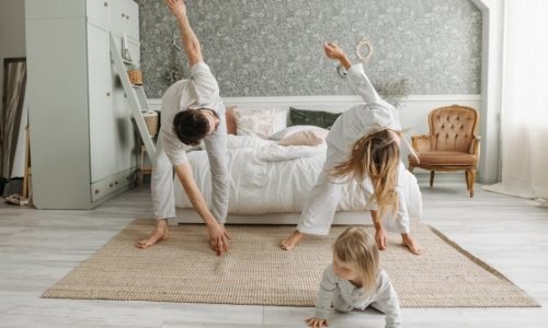 A family stretches together in a cozy bedroom, enjoying morning activities.